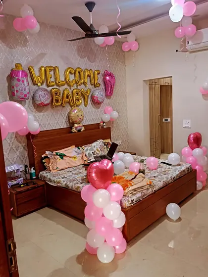 A "Welcome Baby" room decoration for a girl, with pink and white balloons and baby-themed foil balloons.
