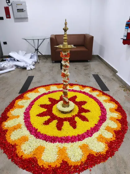 A large floral rangoli, or 'pookalam', created for a corporate event at Trans cosmos. The traditional lamp in the center adds an auspicious touch.
