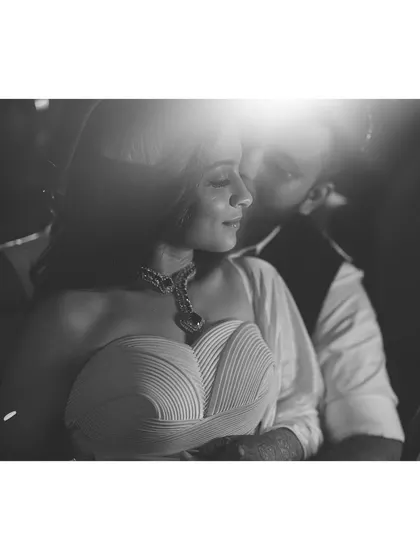 A quiet, artistic moment between the couple. This black and white shot highlights the textures of their outfits, from the bride's sculpted bodice to the groom's sharp tailoring.