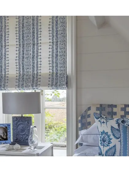 This bedroom showcases how classic blue and white fabrics can be used for Roman blinds and coordinating cushions to create a serene and cohesive look. It's a timeless palette that always feels fresh.