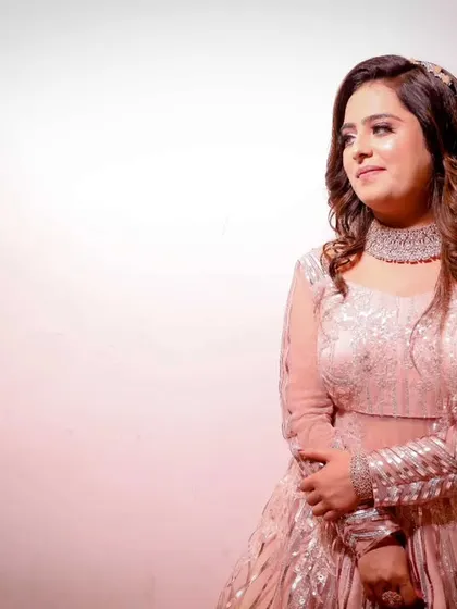 A lovely colour portrait of the bride-to-be at her engagement. Her pastel gown and radiant smile are highlighted against a soft pink background.