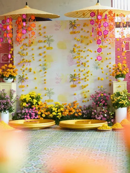 The main seating area for the Haldi, featuring a backdrop of falling marigolds and traditional umbrellas. This setup provided a beautiful and auspicious spot for the couple's ceremony.