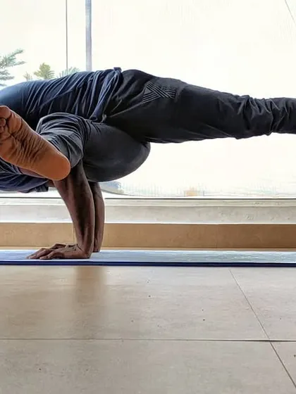 Working on Eka Pada Koundinyasana I, an arm balance that requires a deep twist and core strength. The big window in the studio makes it feel like you're flying among the trees.