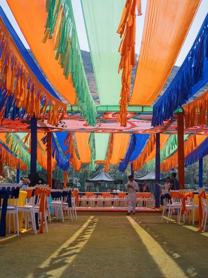 The ceiling decor for the Mehendi, with colorful fabric drapes creating a tent-like effect. This is a great way to add color and create a festive atmosphere in an outdoor space.