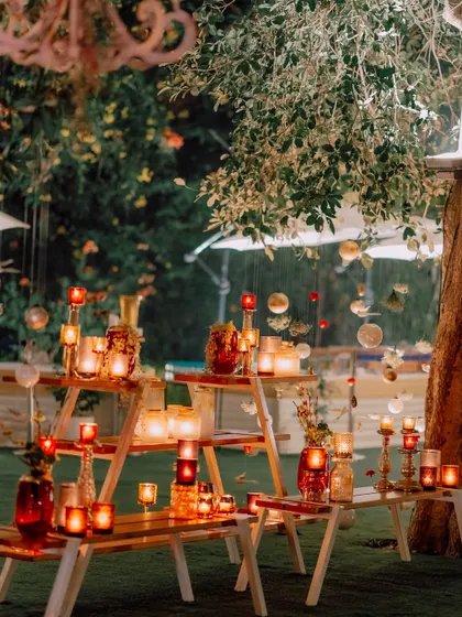 A creative display of candles on rustic wooden benches, adding layers of light and warmth to the outdoor space.