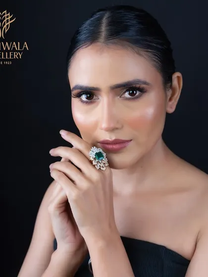 A magnificent pear-shaped emerald is surrounded by a floral-inspired halo of diamonds. This ring is a celebration of color and form, designed to be a conversation starter.