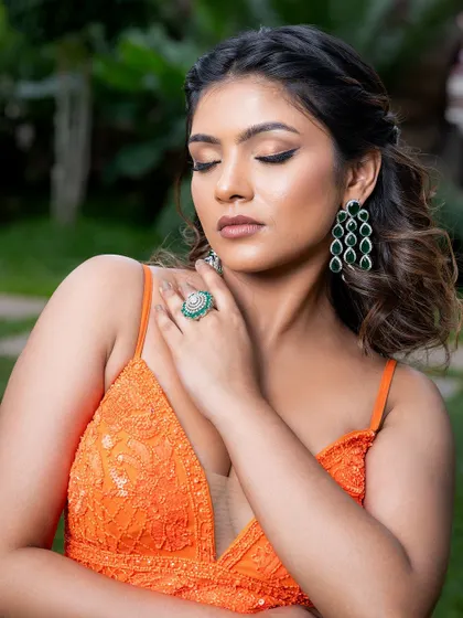 For a pop of color, this emerald green ring and matching tiered earrings are a perfect choice. They add a luxurious and vibrant touch to this orange gown.