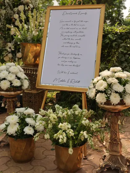 A close-up of the welcome sign and the surrounding floral arrangements in brass pots, a perfect first impression for guests.