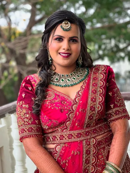 A full view of Supriya's reception look. The makeup is designed to stand out and complement her ornate red and green jewelry.