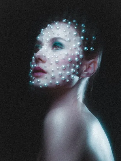Another angle of the pearl makeup, looking upwards into the light. This pose highlights the shimmer on the skin and the careful arrangement of the pearls across the facial contours.
