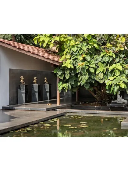A tranquil corner of the museum landscape, where a statue sits beside a lotus pond. The design creates multiple areas for quiet reflection within the larger public space.