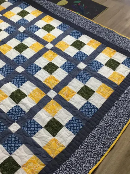 A classic "9-patch" quilt on point, in a blue, yellow, and green color scheme.