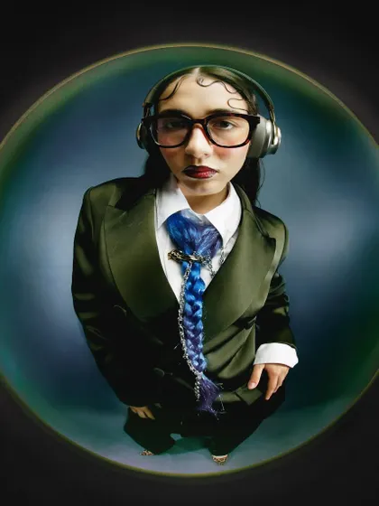 A fisheye portrait featuring a unique braided blue tie. The wide-angle lens emphasizes the styling details and the model's direct, confident expression.