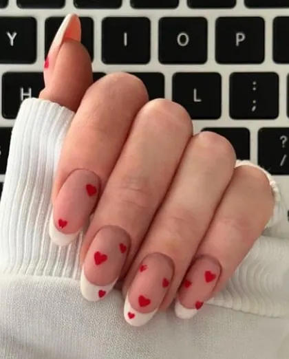 Perfect for Valentine's Day or just to show some love, these oval nails feature a classic French tip with tiny red hearts scattered across a sheer base.