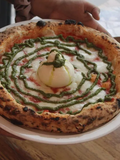 Holding up our Burrata Pesto pizza. It's a showstopper.