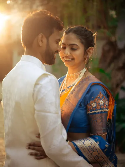A romantic portrait of a couple during golden hour, the warm light beautifully highlighting their traditional attire and happy expressions.
