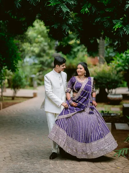 A playful moment as Rutwij holds Apeksha's lehenga while they walk.