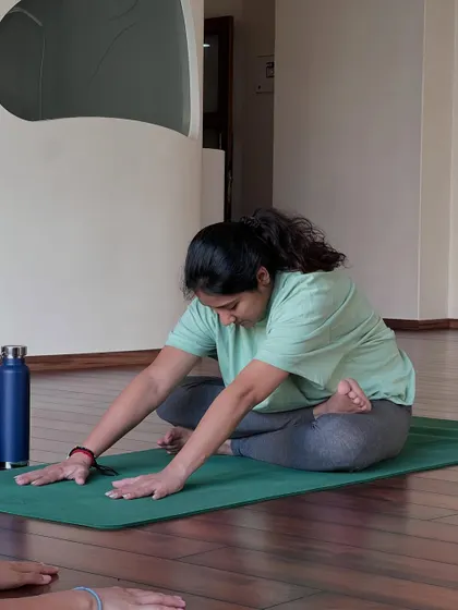 A student practices a gentle forward bend, a modification of Janu Sirsasana. This helps to stretch the hamstrings and back while creating space for the belly.