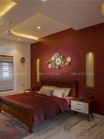 A bedroom with a bold, deep red accent wall that creates a warm and dramatic atmosphere. The traditional wooden bed and metal wall art complete the rich and elegant design.