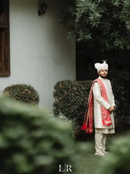 A groom in his traditional sherwani, standing in a garden setting. We capture the groom's portraits with the same artistic attention to detail as the bride's.