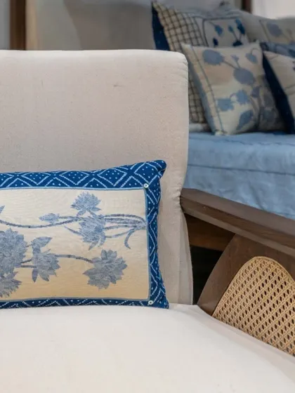 A detail of a custom chair, showcasing the cane handrest and the beautiful indigo-hued Khadi cushion. Every element is chosen to enhance the spatial experience and celebrate craftsmanship.