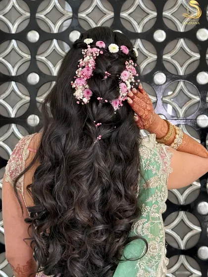 This intricate hairstyle is perfect for a Mehendi celebration. I created a cascading floral design with pink flowers and baby's breath woven through a pull-through braid on top of long waves.