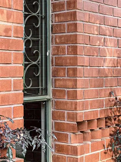 A corner detail showcasing the precision of the bricklaying. The projecting bricks create a dynamic pattern of light and shadow, adding visual interest to the facade.