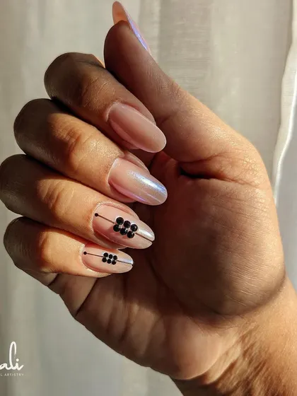 The sunlight catching the pearlescent finish of these extensions, highlighting the subtle shimmer and the bold contrast of the black crystals.