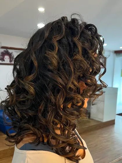 A side view showing the beautiful shape of the medium-length curly cut.
