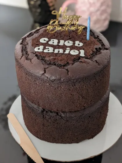 This is my two-tiered rich chocolate cake, perfect for larger birthday parties. It’s made entirely with whole wheat and jaggery, offering a healthier yet delicious option for your celebration. I can add names and a 'Happy Birthday' topper to make it extra special.