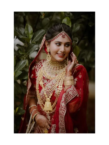 A duplicate of a stunning portrait of a bride in a rich red lehenga, her regal pose and intricate jewelry creating a look of timeless elegance.