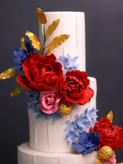 A close-up of the vibrant, handcrafted sugar flowers on the modern white tiered cake.