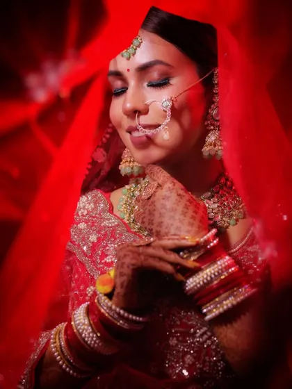 A stunning bridal portrait captured under dramatic red lighting. The bride's serene expression and the rich colors create a powerful and artistic image.