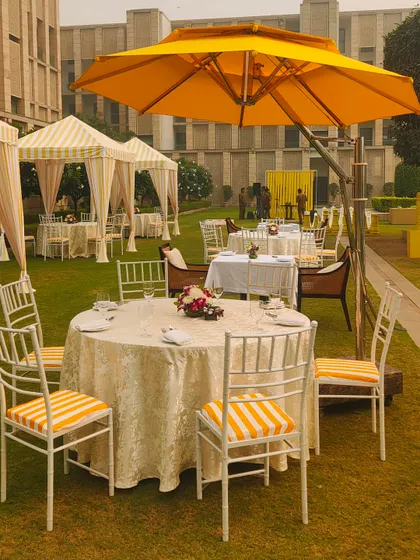 A table setting at the brunch event, showing the striped chair cushions and a large yellow umbrella providing shade. Every detail is coordinated to enhance the cheerful and sophisticated theme.