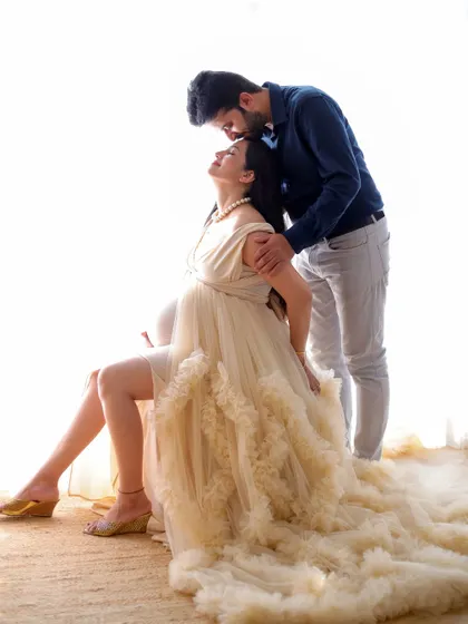 An intimate high-key portrait of an expecting couple. The soft, bright lighting and tender pose highlight the emotional connection and anticipation.