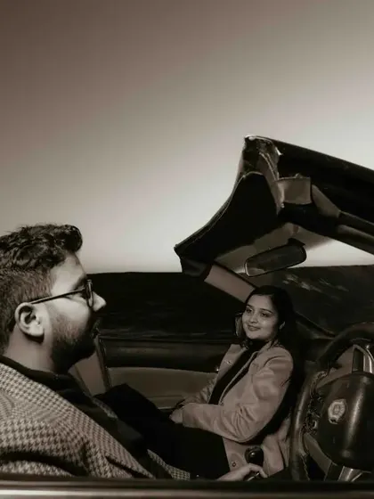 A sepia-toned shot from inside the car, capturing a sweet, smiling interaction between the couple.
