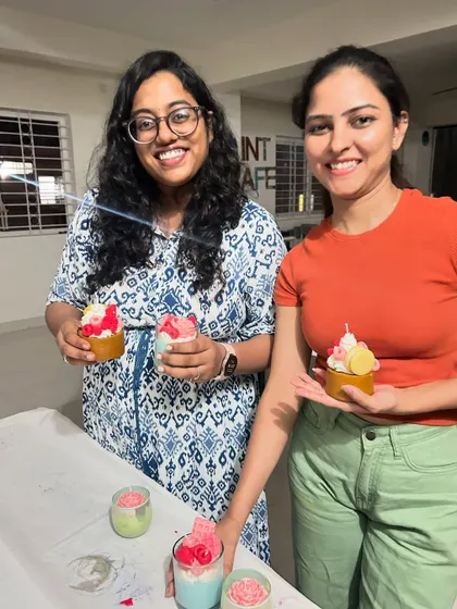 Two participants happily holding up their finished cupcake and dessert-style candles. The smiles show the fun and satisfaction of creating something with your own hands.