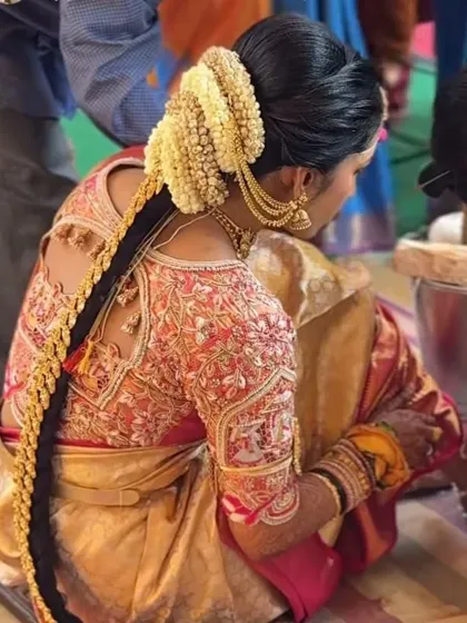 A candid shot of a bride during a ceremony, showcasing the durability and beauty of her traditional braid with gold jewellery and jasmine flowers.