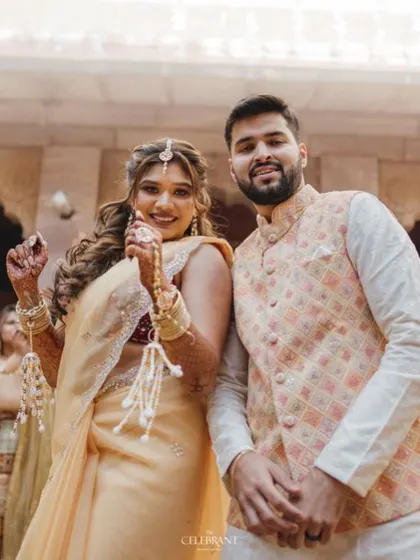 The happy couple posing for a photo. The bride is wearing our minimal yet elegant fresh floral jewellery, including a maang tikka and haath phool.