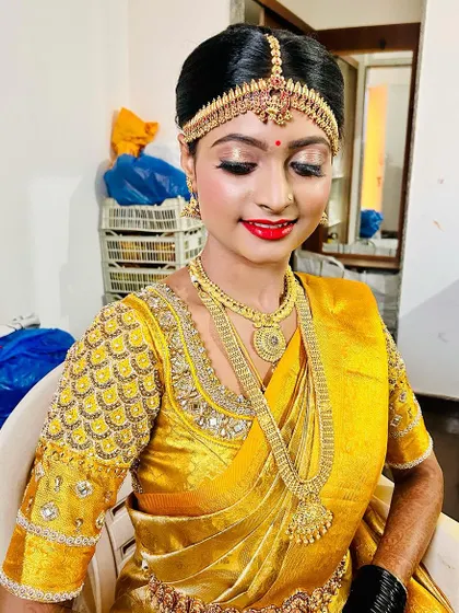 A happy bride ready for her muhurtham. This shot captures the bright, flawless makeup, including the golden eyeshadow and bold red lip, which are classic choices for a traditional ceremony.