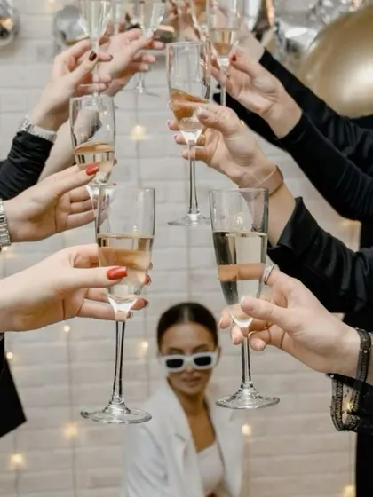 A creative group shot idea for a bachelorette party, with the bride in focus and her friends raising a toast in the foreground.