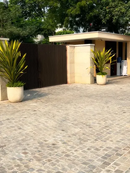 The entrance to the farmhouse, featuring a cobblestone driveway and large potted plants flanking the gate. The first impression is critical, and I design entrances to be both grand and welcoming.