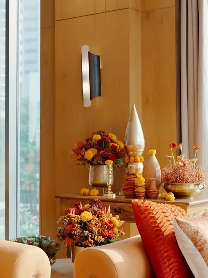 A beautifully styled corner in a luxury home for a traditional function, with brass vases, marigold arrangements, and decorative cones.