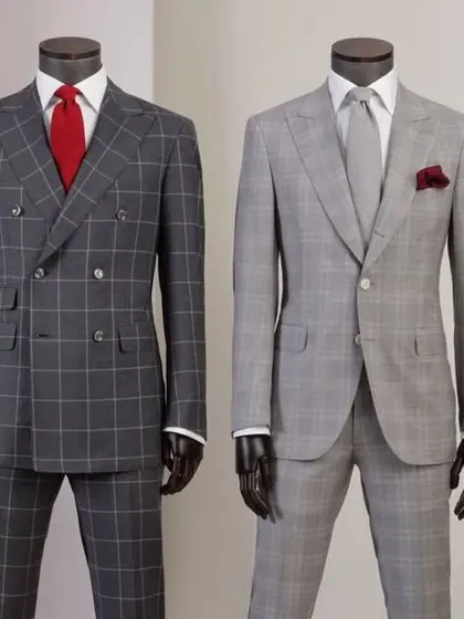 A comparison of two classic checked suits. On the left, a bold grey windowpane check in a double-breasted style, and on the right, a subtle plaid single-breasted suit.
