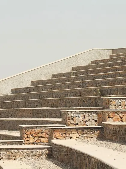 The tiered seating of the amphitheatre follows the natural contours of the hill. The combination of rough stone-filled gabions and smooth concrete tops creates a textural contrast that is both rustic and refined.