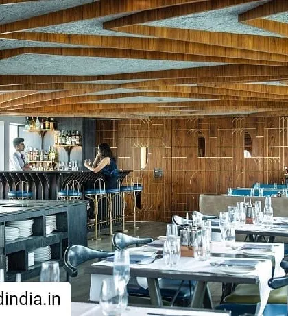 The interior of the main dining level, showcasing the intricate, curved teak wood elements that define the space. The design balances sophisticated aesthetics with practical restaurant functionality, including integrated service stations and varied seating arrangements.