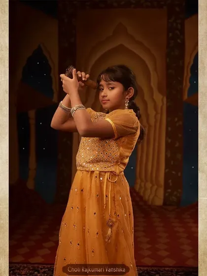 The portrait of Choti Rajkumari Vanshika, the young princess. Her golden-yellow outfit and playful pose with a telescope capture the innocence and curiosity of her character.