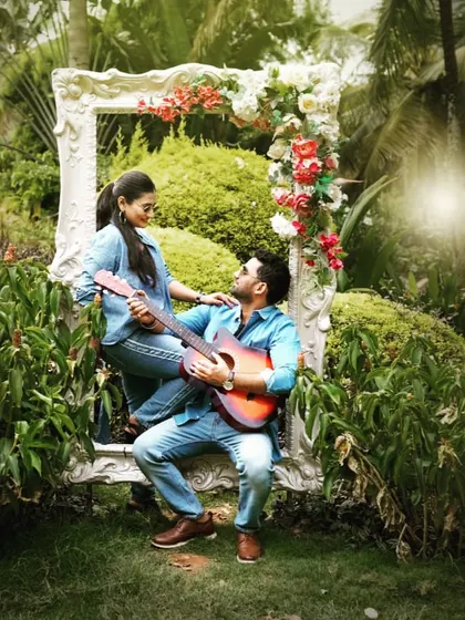 Using a large picture frame as a prop, this pre-wedding photo creates a storybook feel, with the groom serenading his bride in a lush garden.