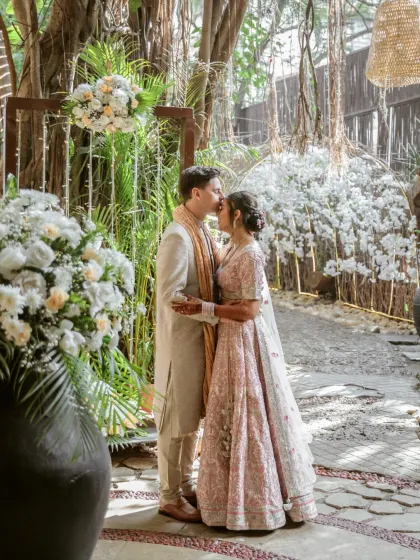A romantic kiss shared by the couple amidst beautiful floral decorations. This shot is a perfect example of how I blend intimate moments with the stunning aesthetics of the wedding decor.