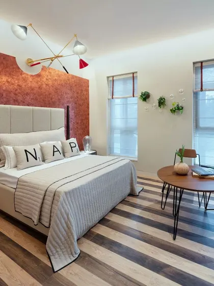 A bedroom with a bold, textured accent wall and unique lighting, demonstrating a more maximalist approach.